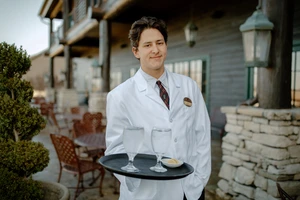 Young man holding tray of drinks.